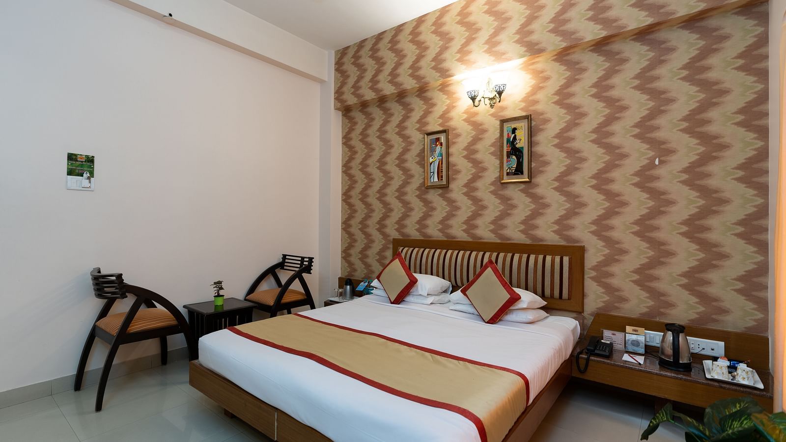 A double bed with chairs next to it inside one of the rooms - Hotel Pai Vista, KR Road
