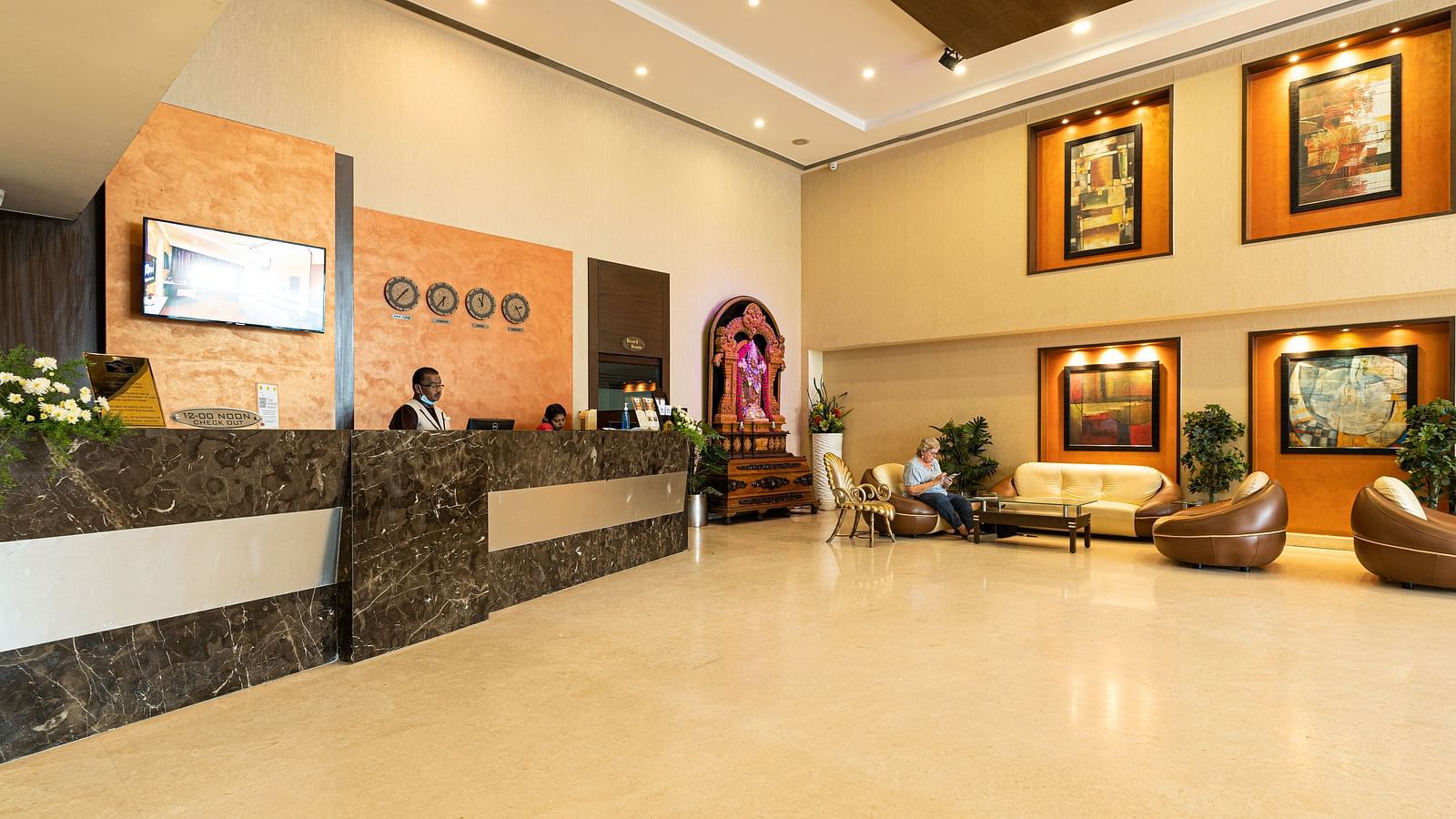 A reception area with people sitting behind the desk - Hotel Pai Vista, Mysore - Mysore Hotel Contact Number