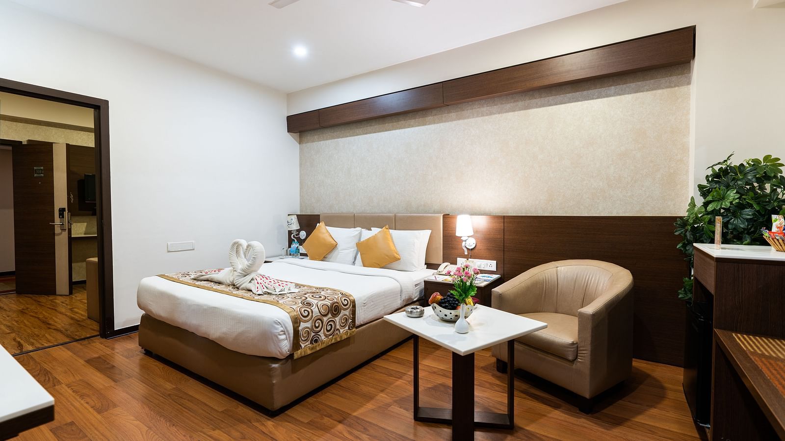 a double bed with a single seater sofa next to it inside one of the rooms - Hotel Pai Vista, Mysore
