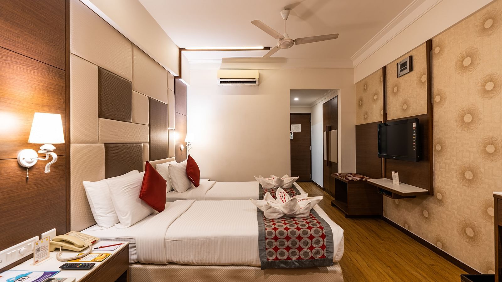 twin beds in front of a wall mounted tv in one of the rooms - Hotel Pai Vista, Mysore