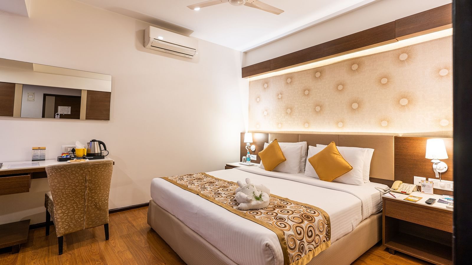 a double bed with a study table next to it inside one of the rooms - Hotel Pai Vista, Mysore