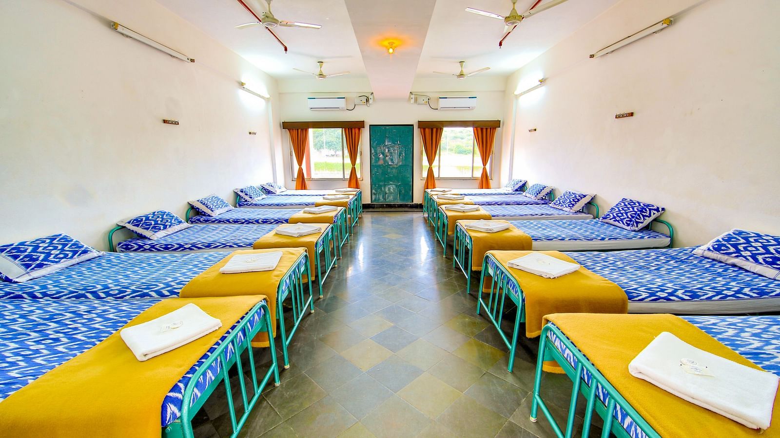 Multiple chairs around the circumference of long rectangular tables for dining at Hotel Sahara - Dining Area in Ramoji Film City, Hyderabad.