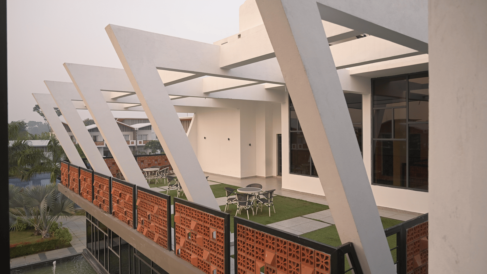 Side view of the rooftop featuring geometric white beams and open-air seating at Hotel Sonar Bangla Mayapur.