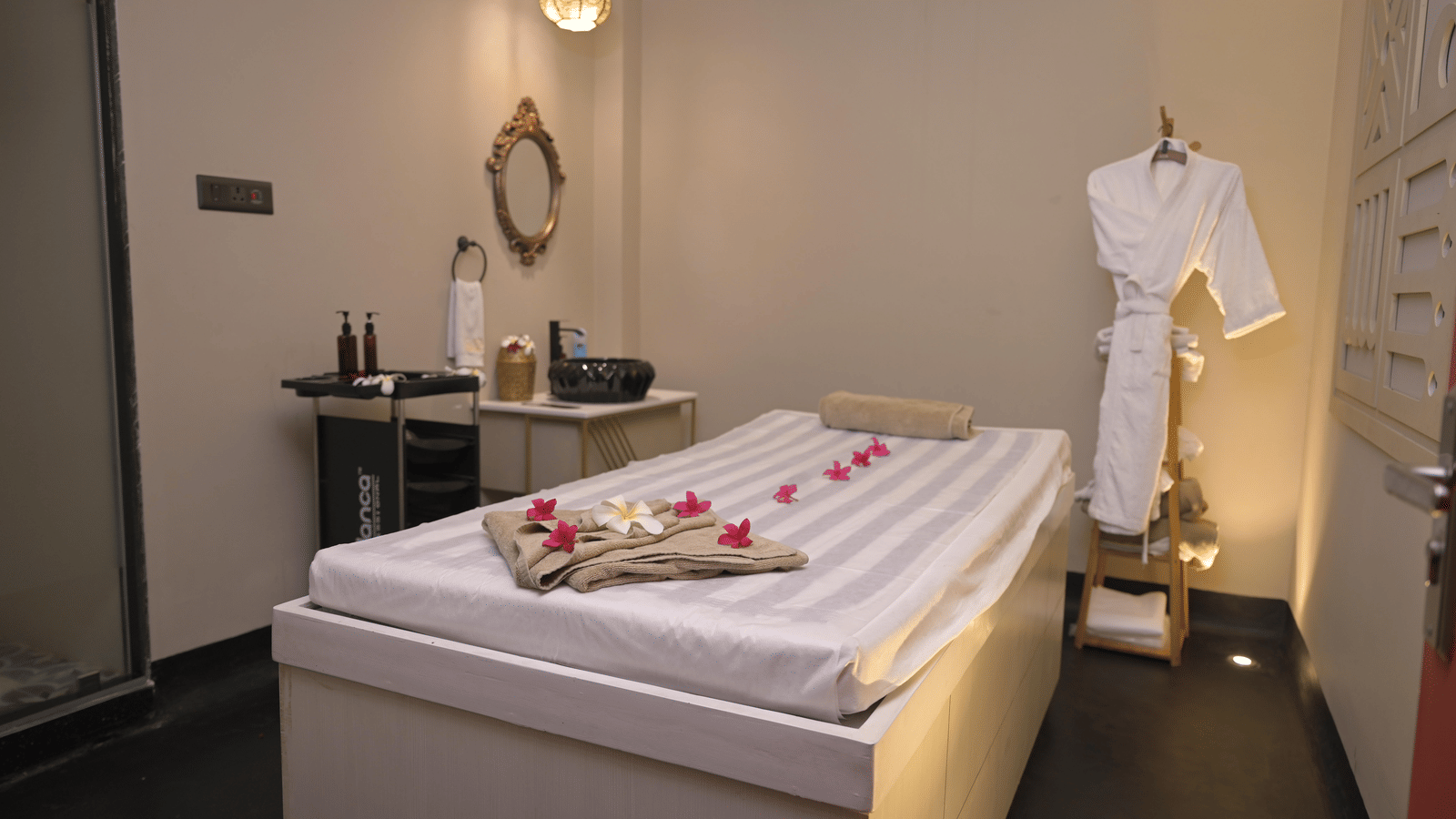 A spa room with a neatly arranged massage bed and treatment essentials at Hotel Sonar Bangla Mayapur.