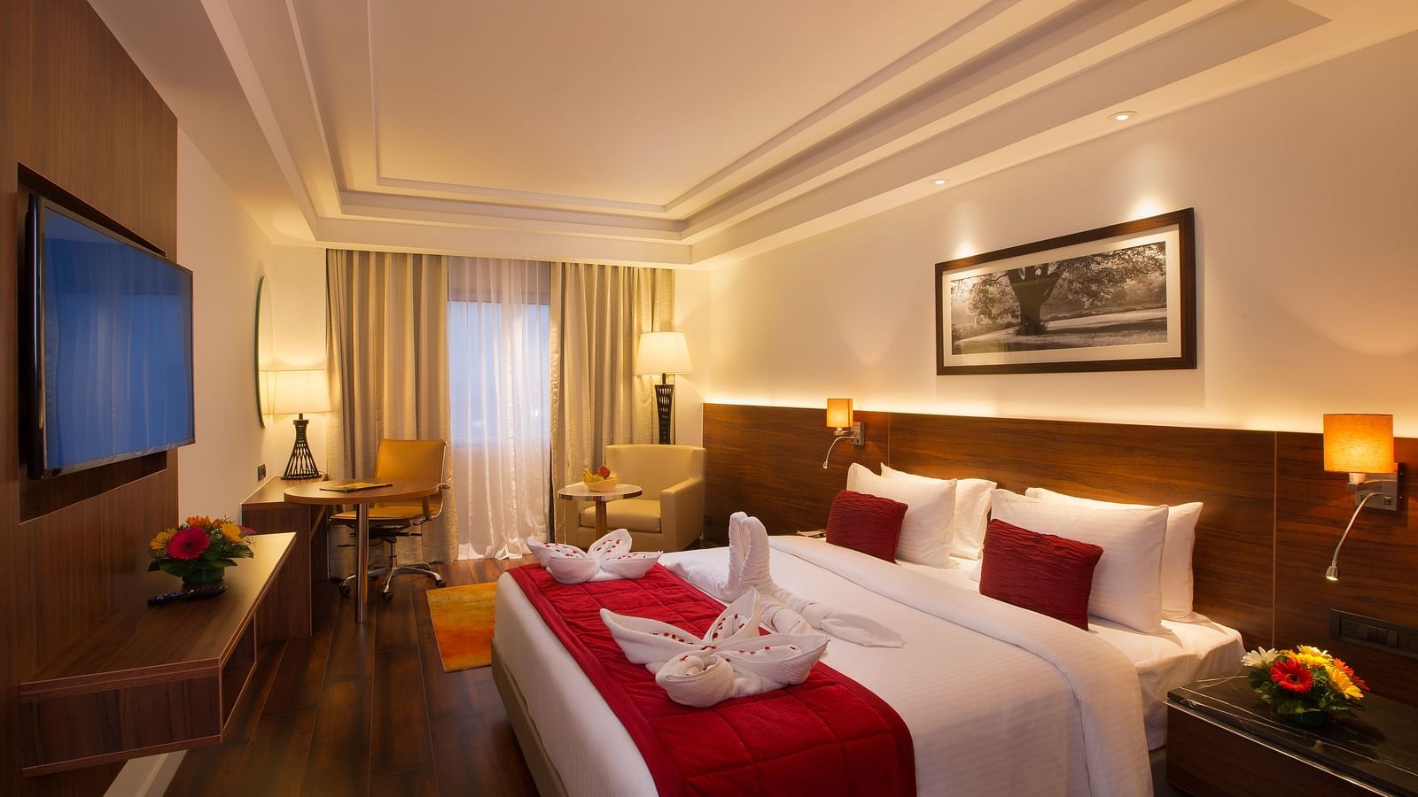 An elegant hotel room with a large bed, red throw blanket, decorative pillows and a framed black-and-white photograph on the wall - Hotel Southend by TGI - Bommasandra, Bangalore