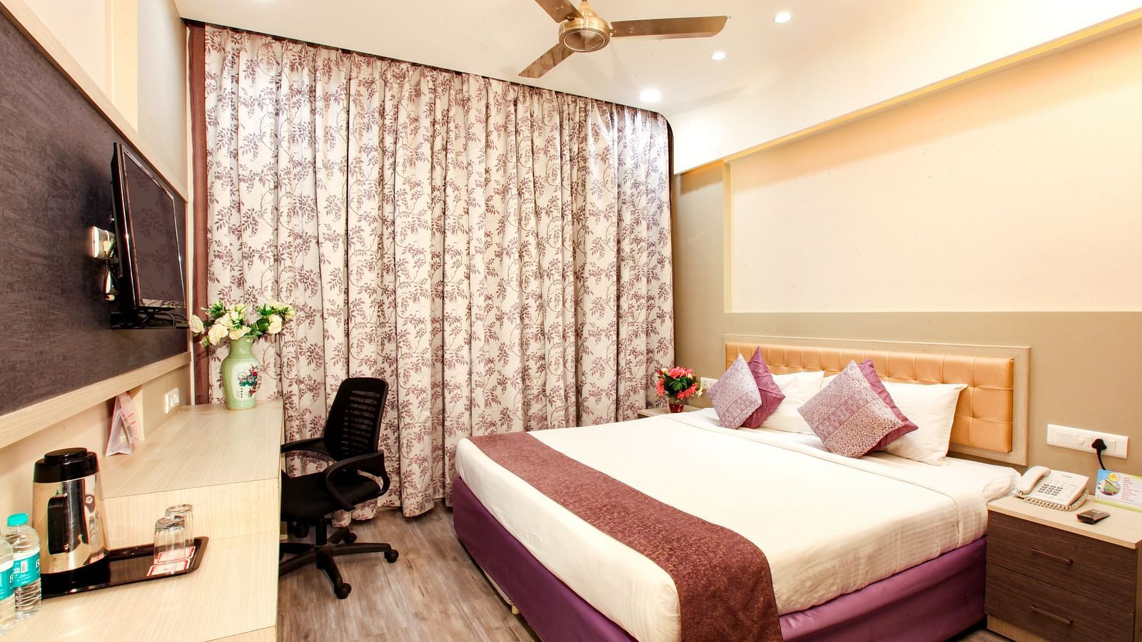 A well-appointed hotel room with a patterned headboard and modern amenities. - Tara, Comfort Hotel in Hyderabad - Ramoji Film City.