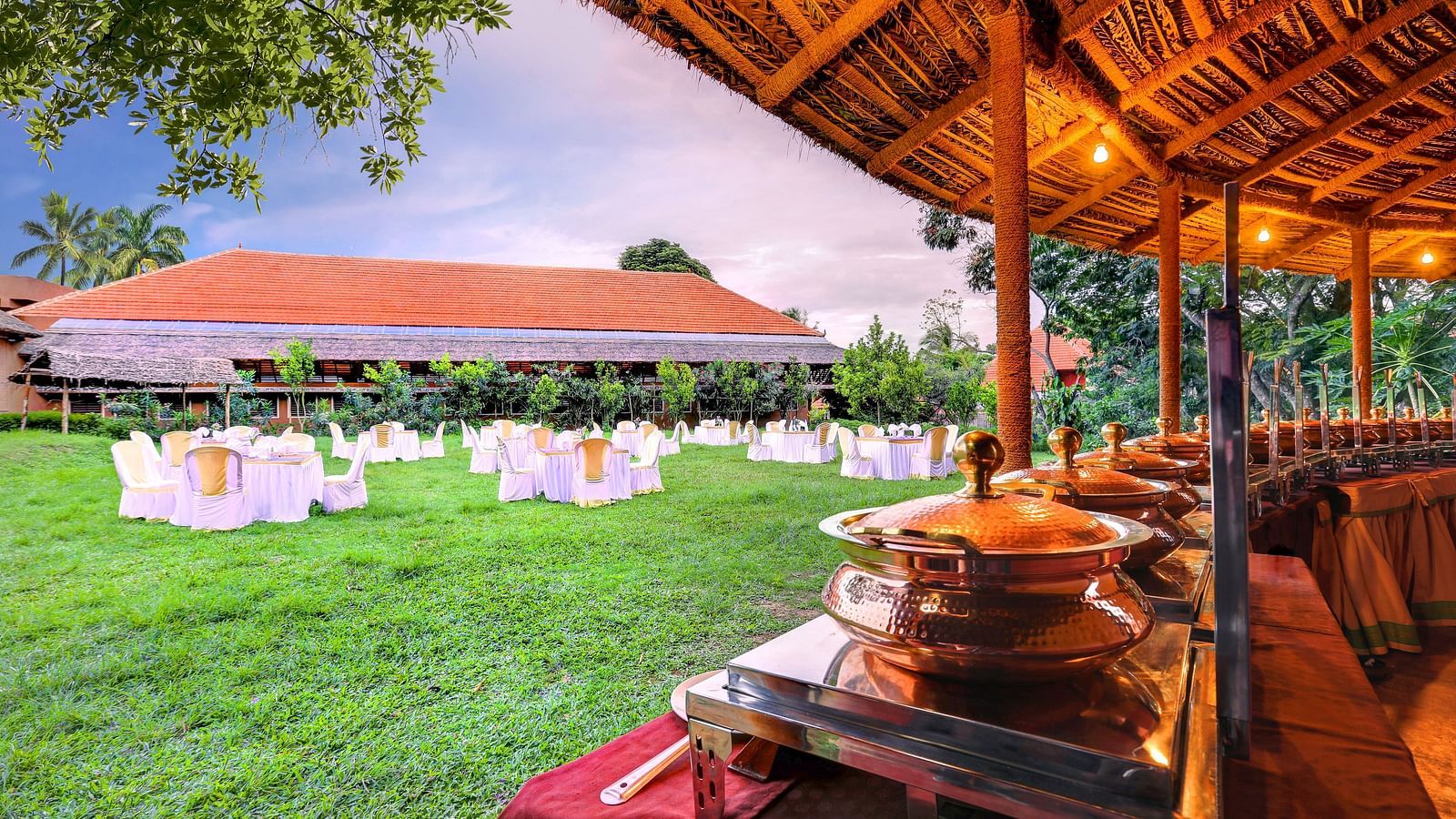 An overview of the lawn area as seen from the restaurant with elaborate seating arrangements at hoysala village resort.