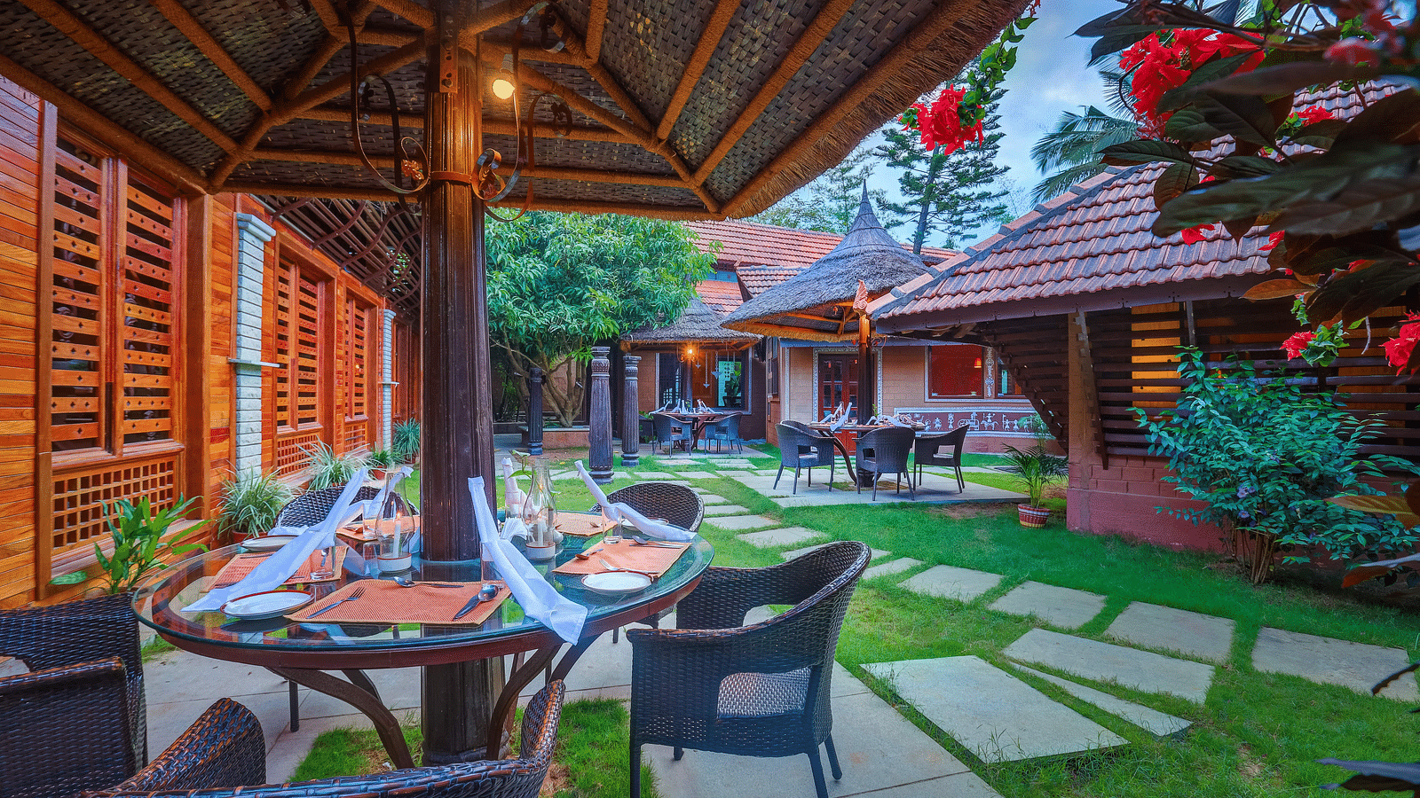 image of the open garden dining area with beautiful serene backdrop of exotic flora at hoysala village resort, hassan