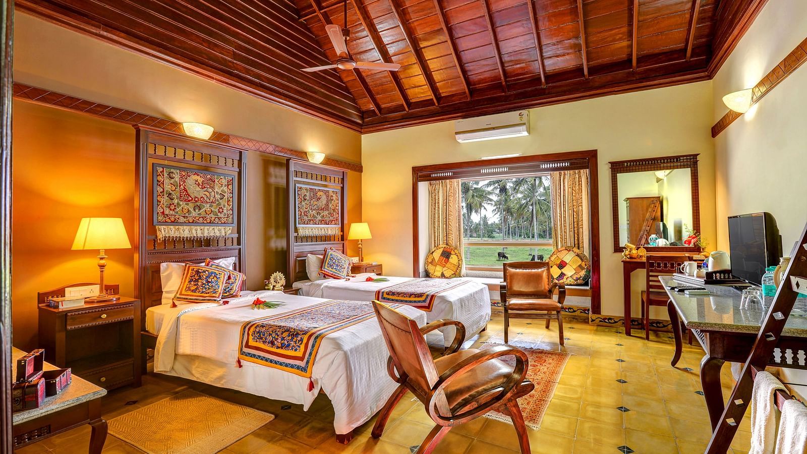 An image of a bedroom with seating area, open windows, lamp, dressing table, etc. -  Hoysala Village Resort, Hassan