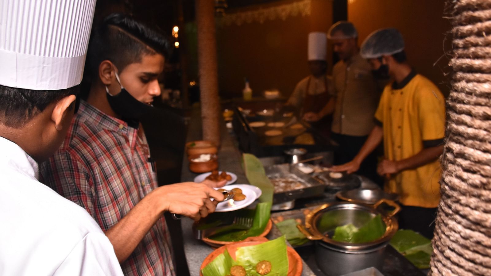 image of a guest placing food on his plate from the delicious buffet at the garden restaurant of hoysala village resort in hassan