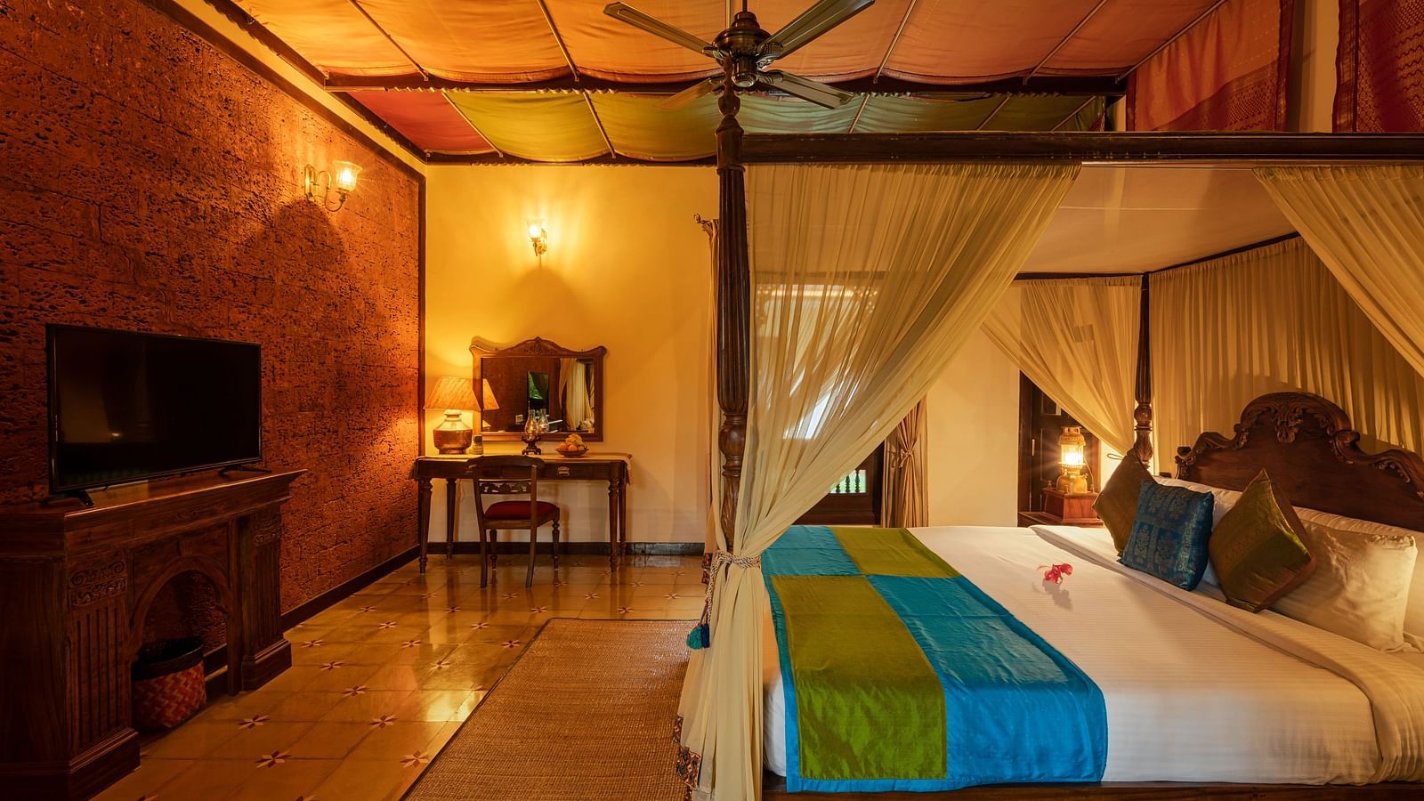 An overview of malnad palace suite with a double bed and tv at hoysala village resort, Hassan.