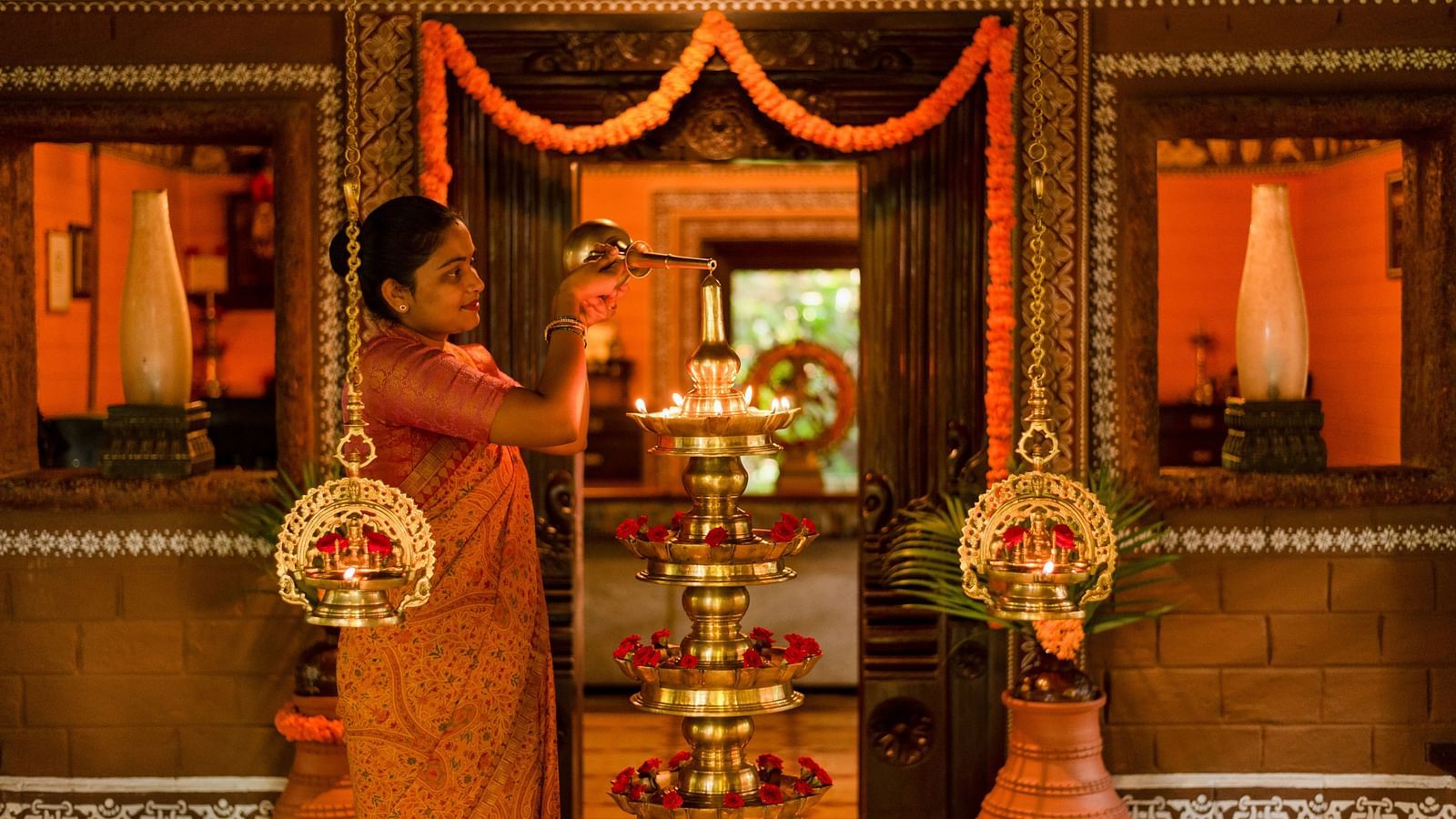 image of a staff pouring oil in the bronze lamp at Hoysala Village Resort, Hassan
