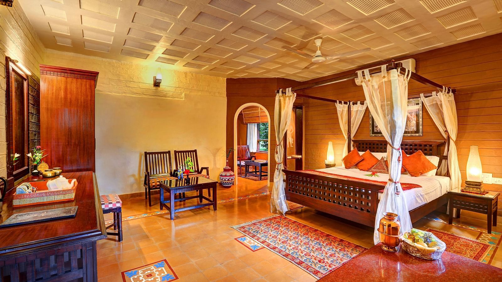 An image of a huge bedroom with poster bed, cupboard, dressing table, centre table, a chair, and many more wooden belongings - Hoysala Village Resort, Hassan