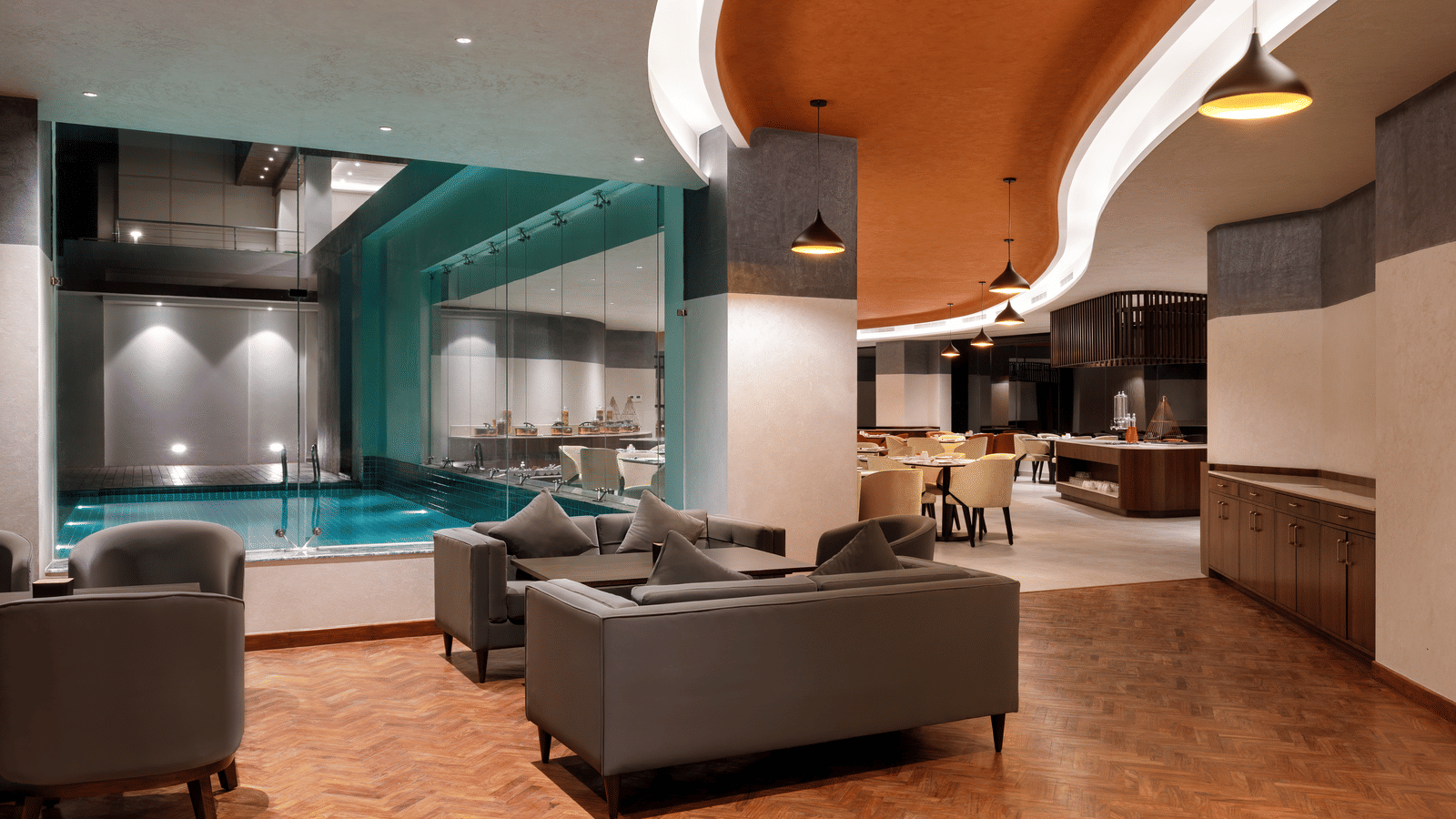 An illuminated dining space with sofas and chandeliers at Ila Resort, Maulakali.