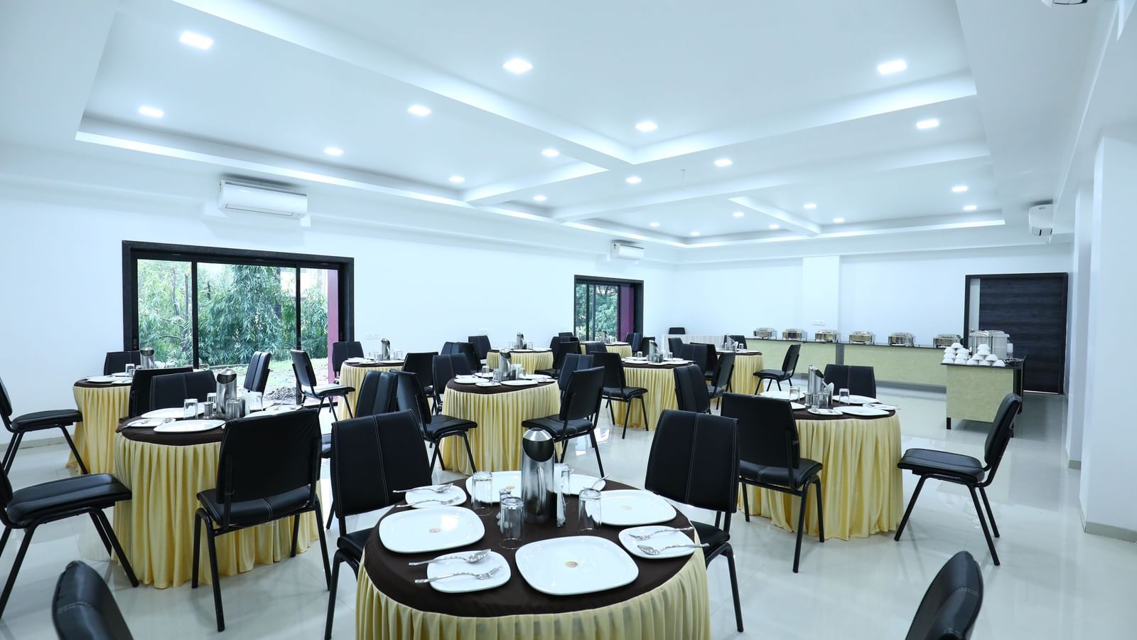 A well-lit dining space at Imperial Grande, featuring a clustered seating arrangement and windows offering a view of the outdoors.