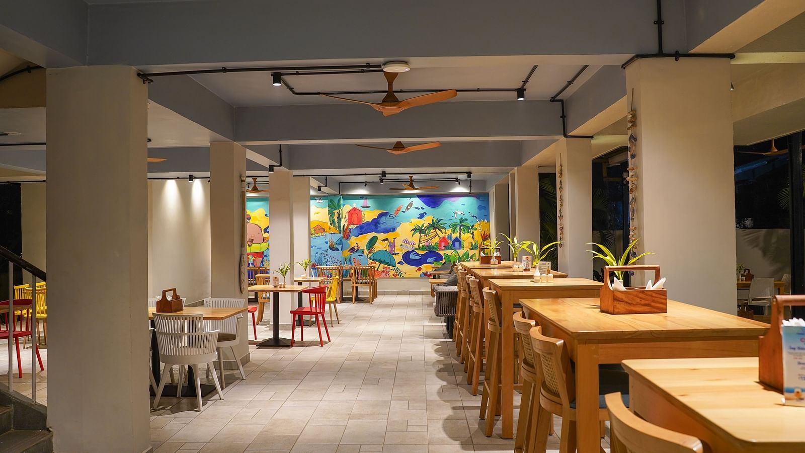 A dining area featuring cartoonish doodles on the wall, with a wooden table and chairs set up for guests at Indie Stays