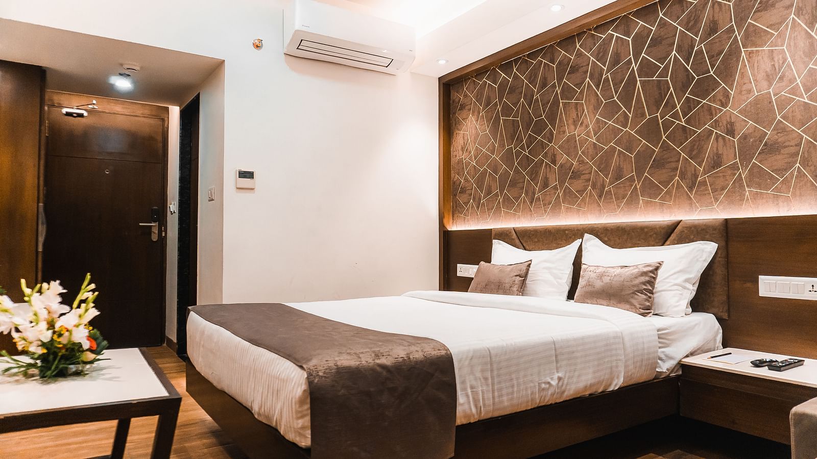 a bedroom with a large bed and side drawer and a table in front - Jardin Hotels