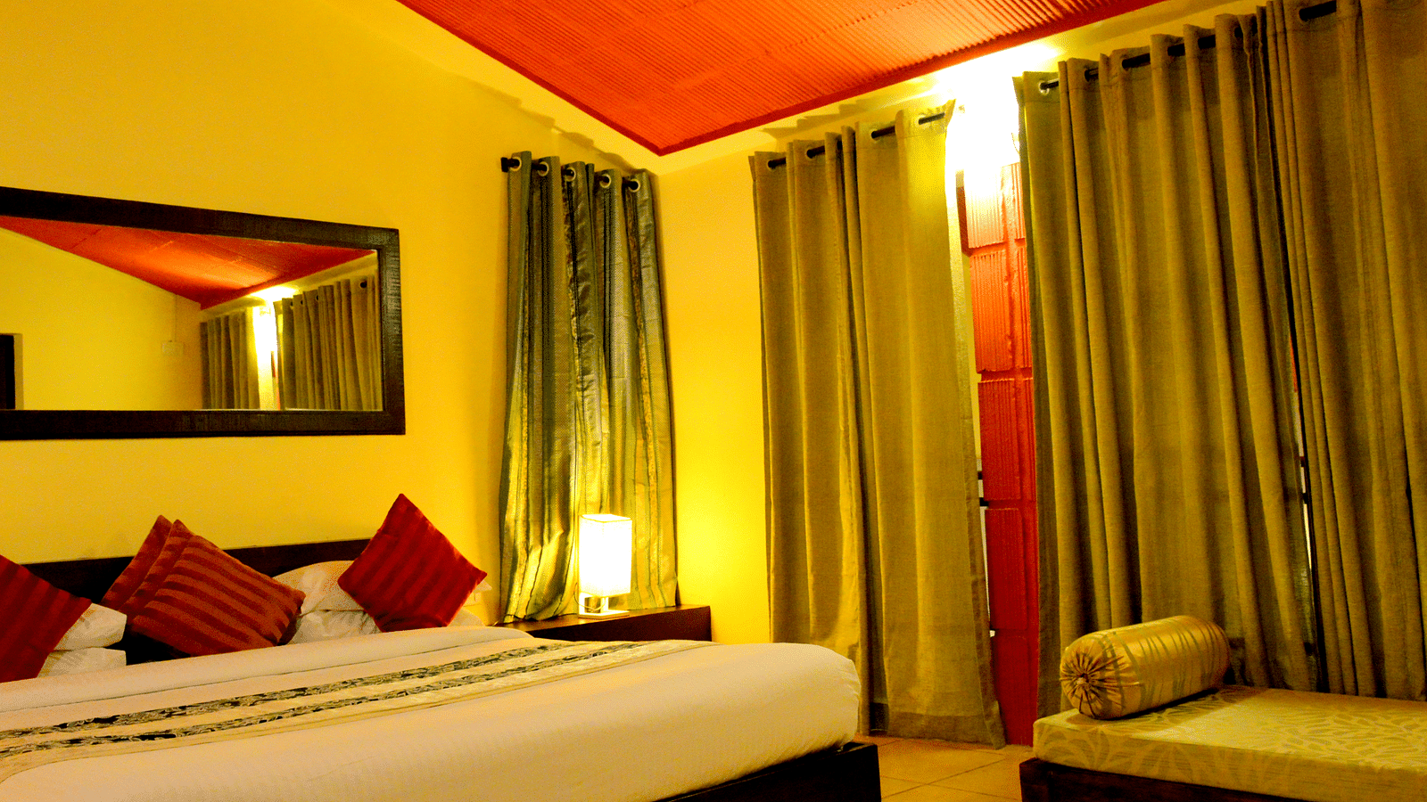 a bedroom with a bed and large curtains and a sofa on the side - Kadkani River Resort, Coorg
