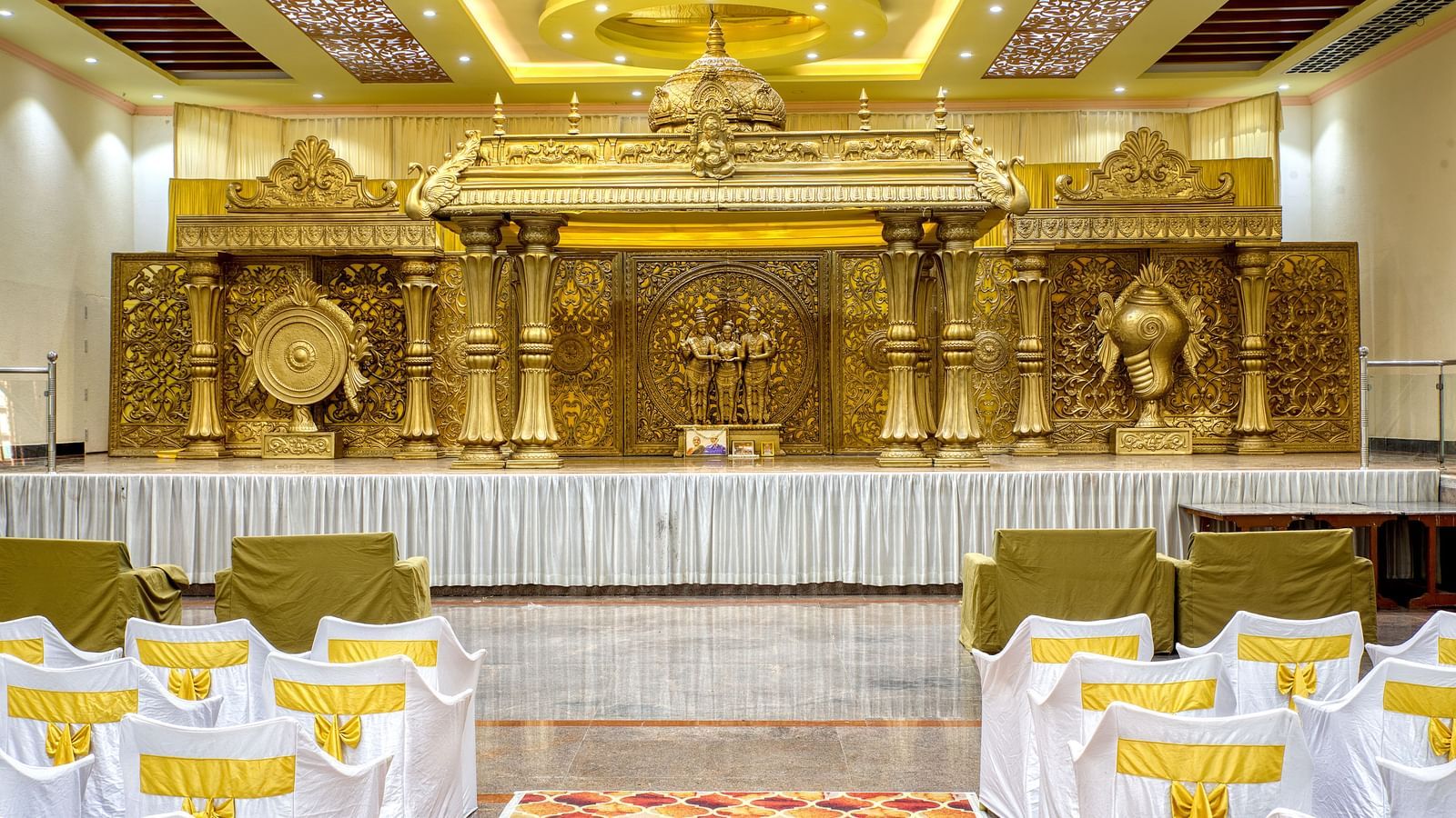 Decorated indoor wedding stage with golden backdrop and banquet seating at Kailash Conventions ECR.