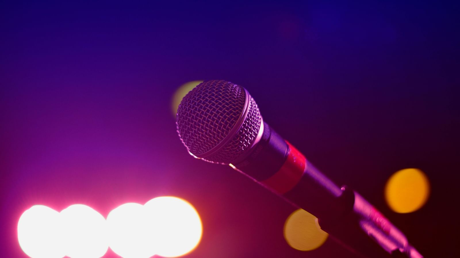 A close up image of a mike with faint lighting in the background
