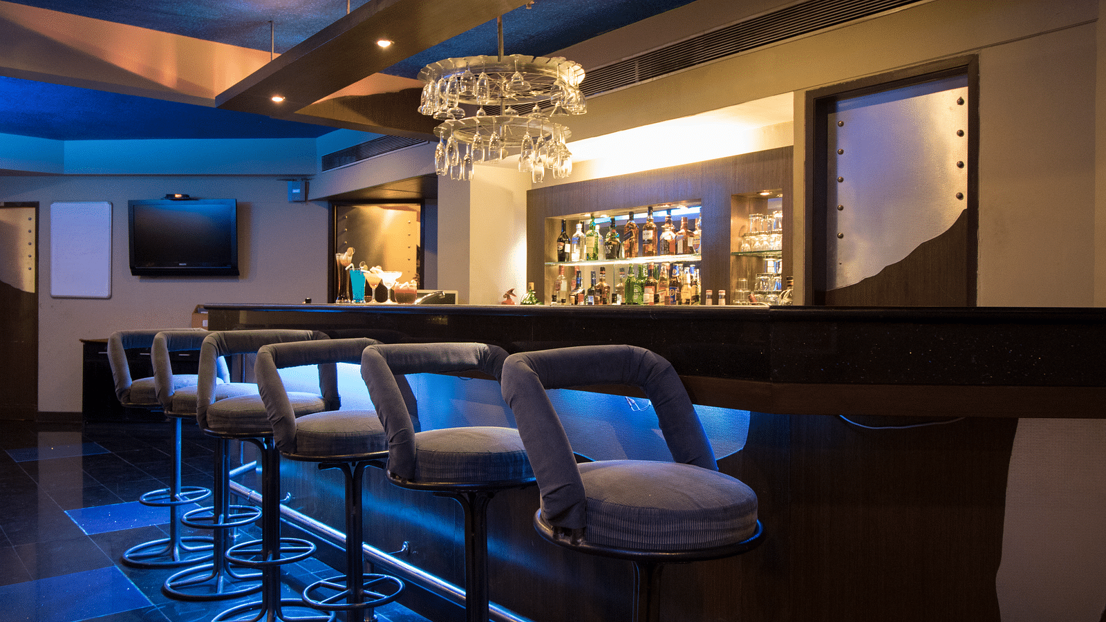 An image of a dimly lit bar which has different brands and types of liquor products - Kamats India