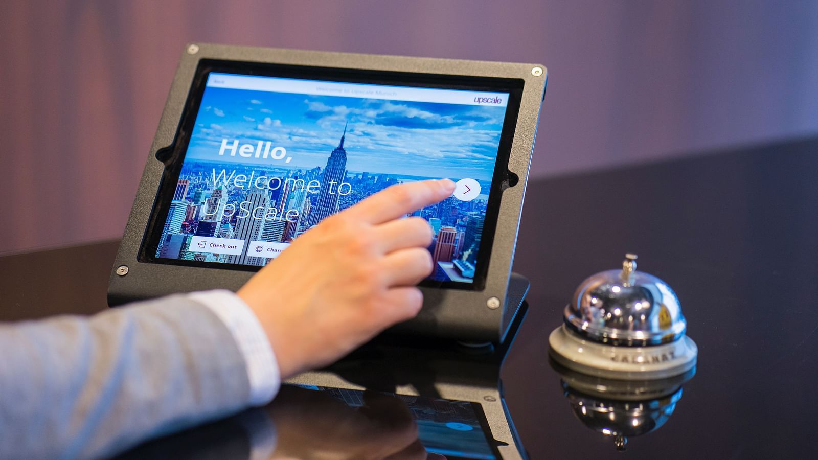 image of a person operating a touch screen tablet with a call bell besides it