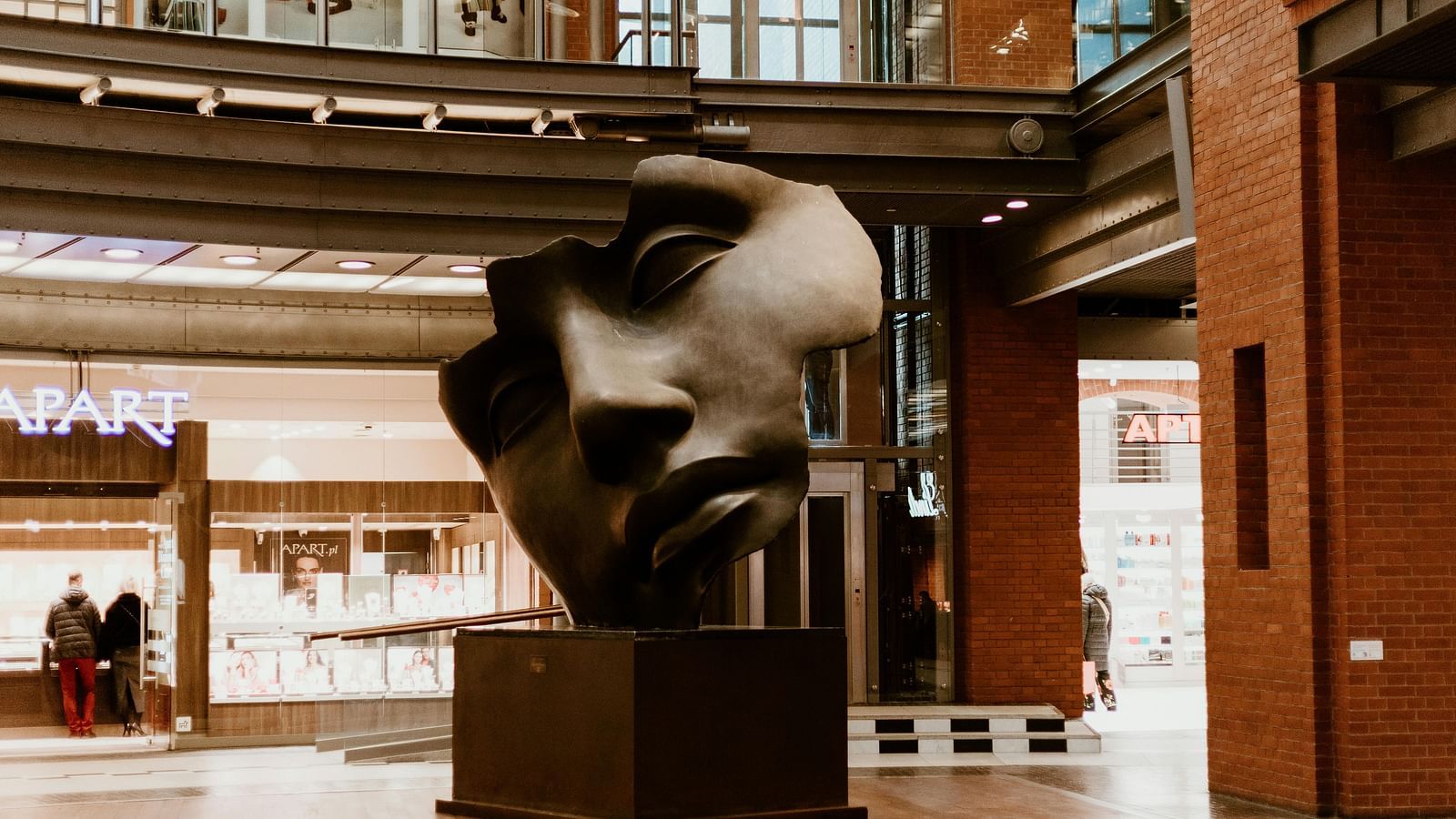 Modern sculpture head in a bright, industrial-style space with warm wood tones and metal accents.