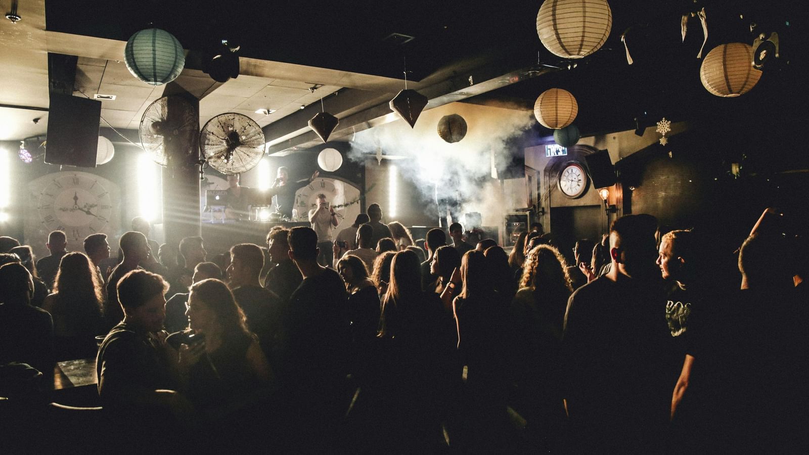 A lively indoor concert scene with bright stage lights shining over a crowd of people, creating an energetic and festive atmosphere.