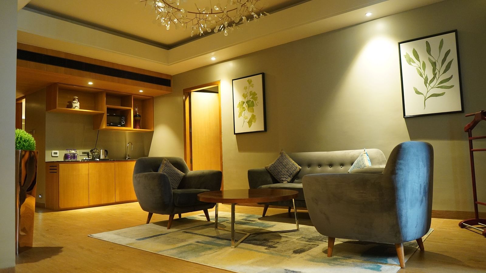 Living room with spacious furniture, a wooden shelf with decorations, and warm lighting