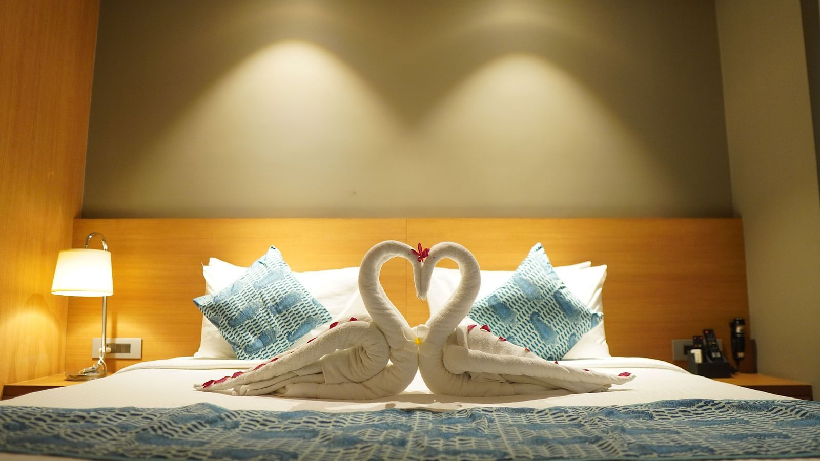 Spacious bed with towels folded into swans and warm lighting