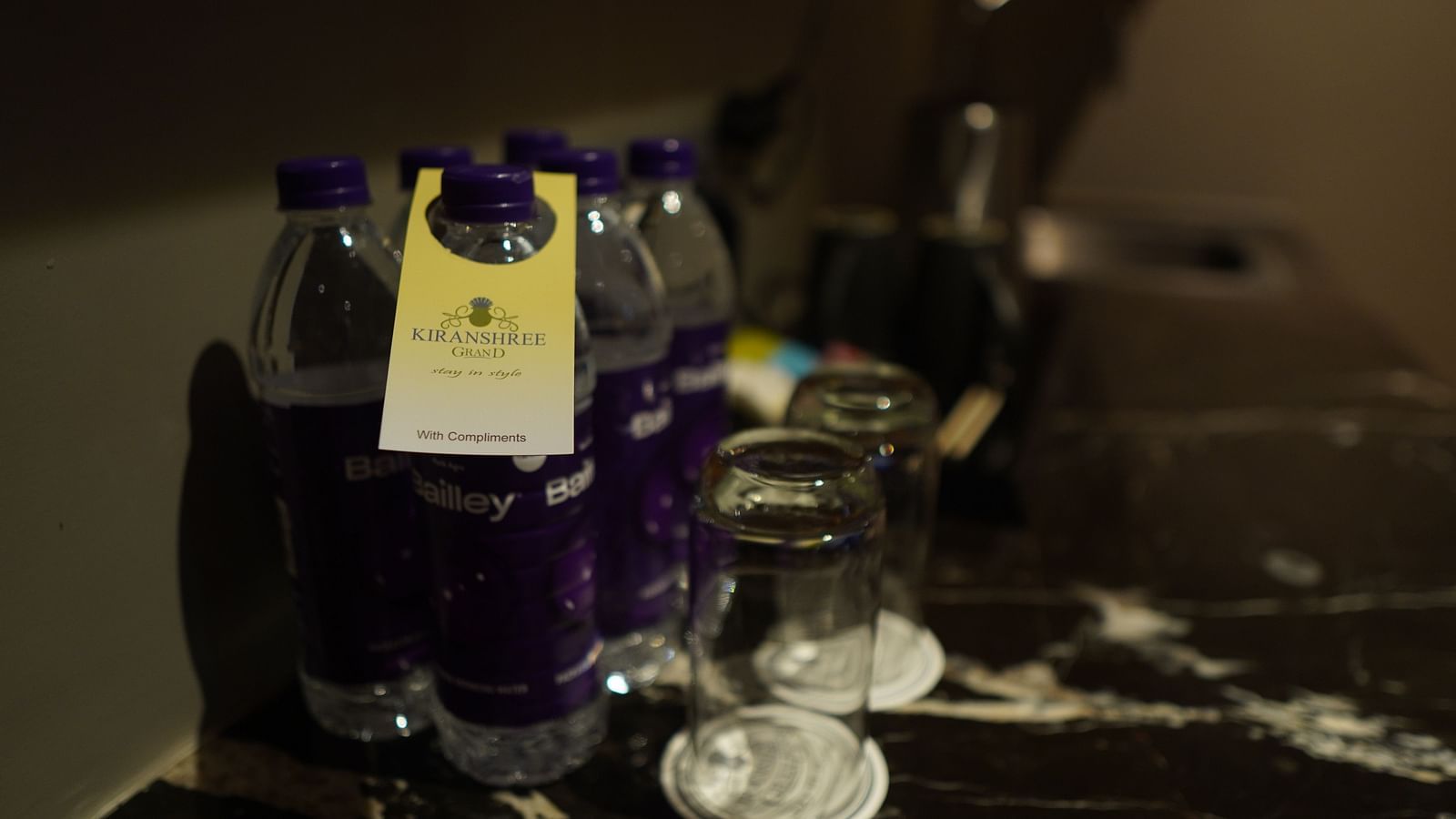 Spacious marble surface with essentials like a water bottle and glasses, featuring the hotel’s tag name.