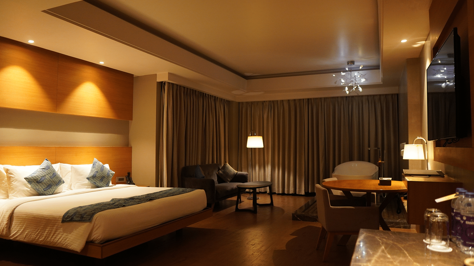 Spacious room with a large bed, cushioned furniture, and closed window curtains