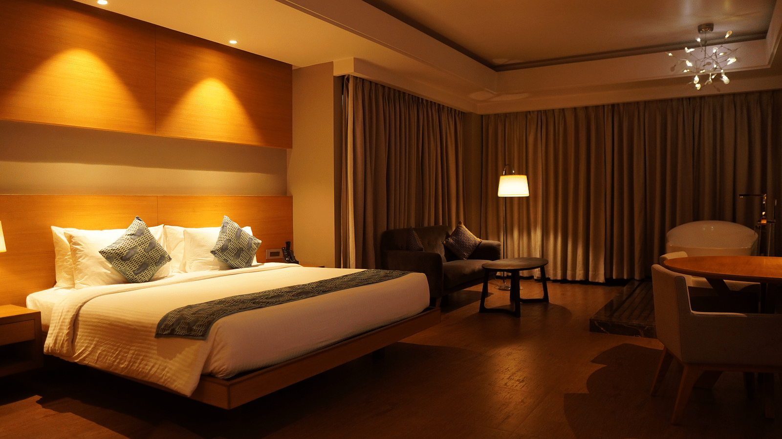 Spacious room with a large bed, cushioned furniture, and closed window curtains