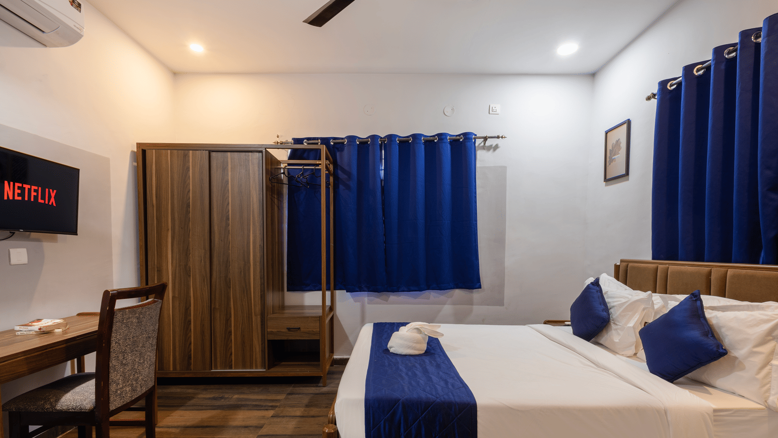 Side view of a Deluxe Room in Kove Smart Stays, showcasing its queen size bed, wardrobe, and wooden flooring.