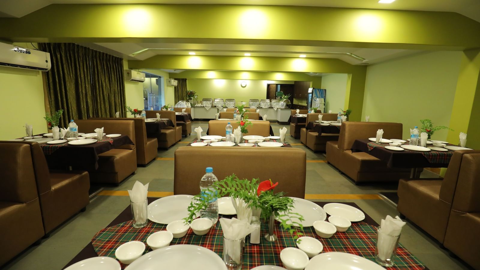 Close-up of tables set with plates and bottles on a carpeted floor at Krushnai Resort.