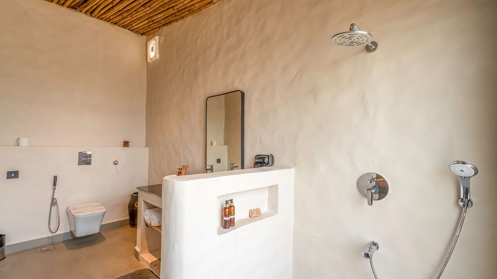 An image of washroom at Kurja Jawai featuring a commode, tap, faucets, shower heads, cabinet with towels, bodywash and shampoo, and other bathroom amenities