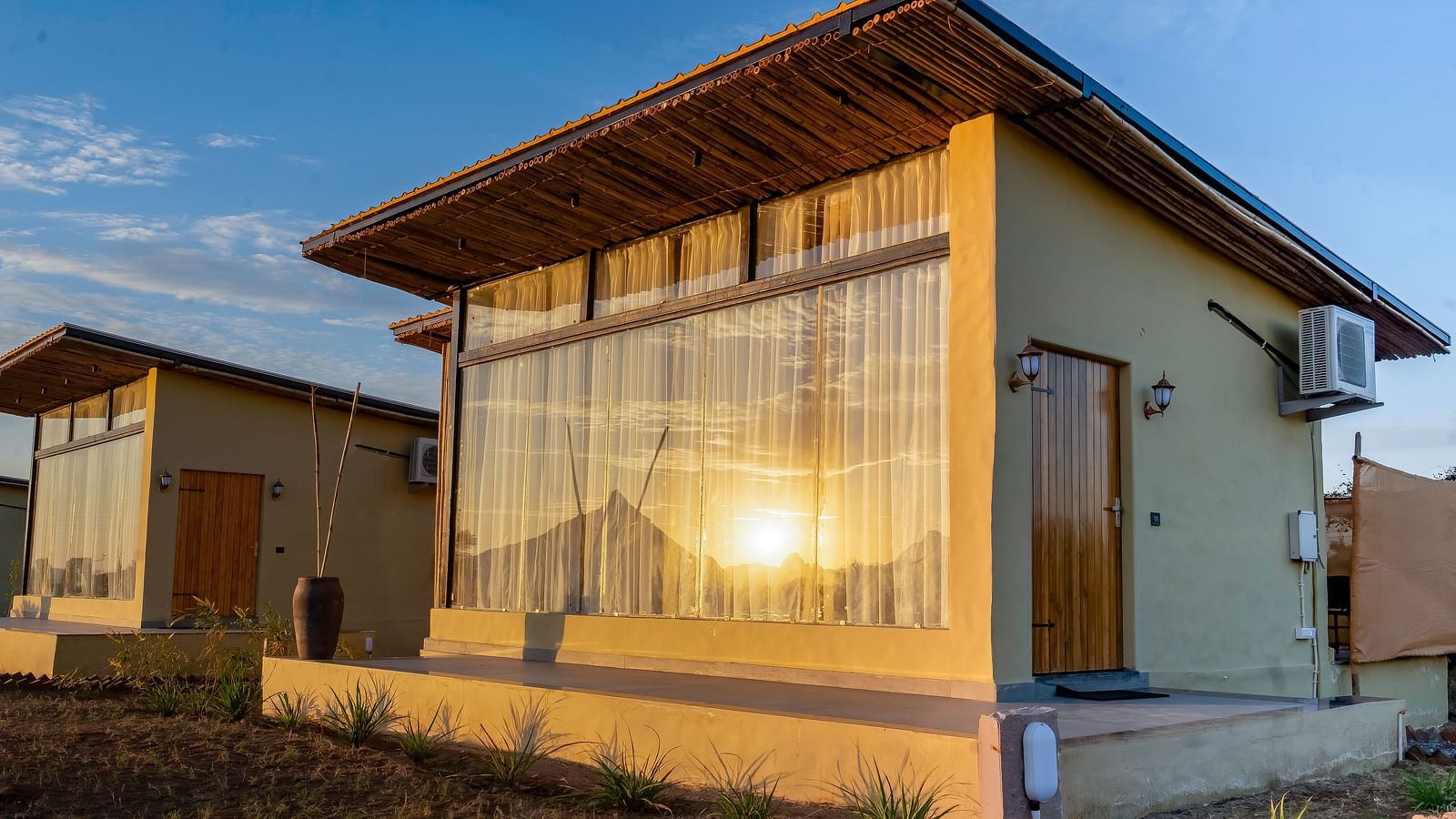 An image of a window of Jungle Cottage where sun is getting reflected and the windows have curtains drawn from inside at Kurja Jawai