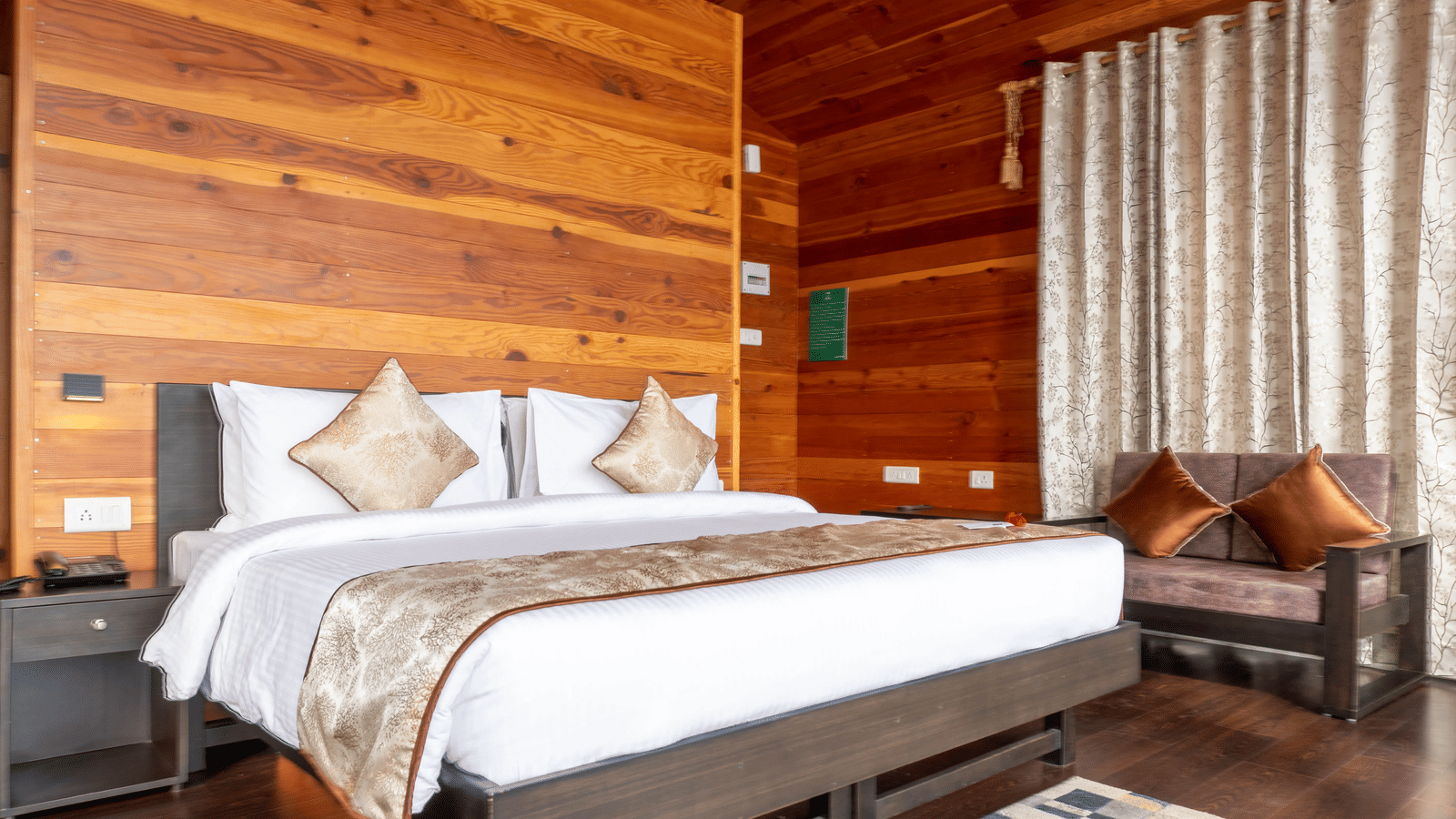 Side angle view of the double bed along with a couch in the corner along with wooden interiors at Le ROI Floating Huts & Eco Rooms.