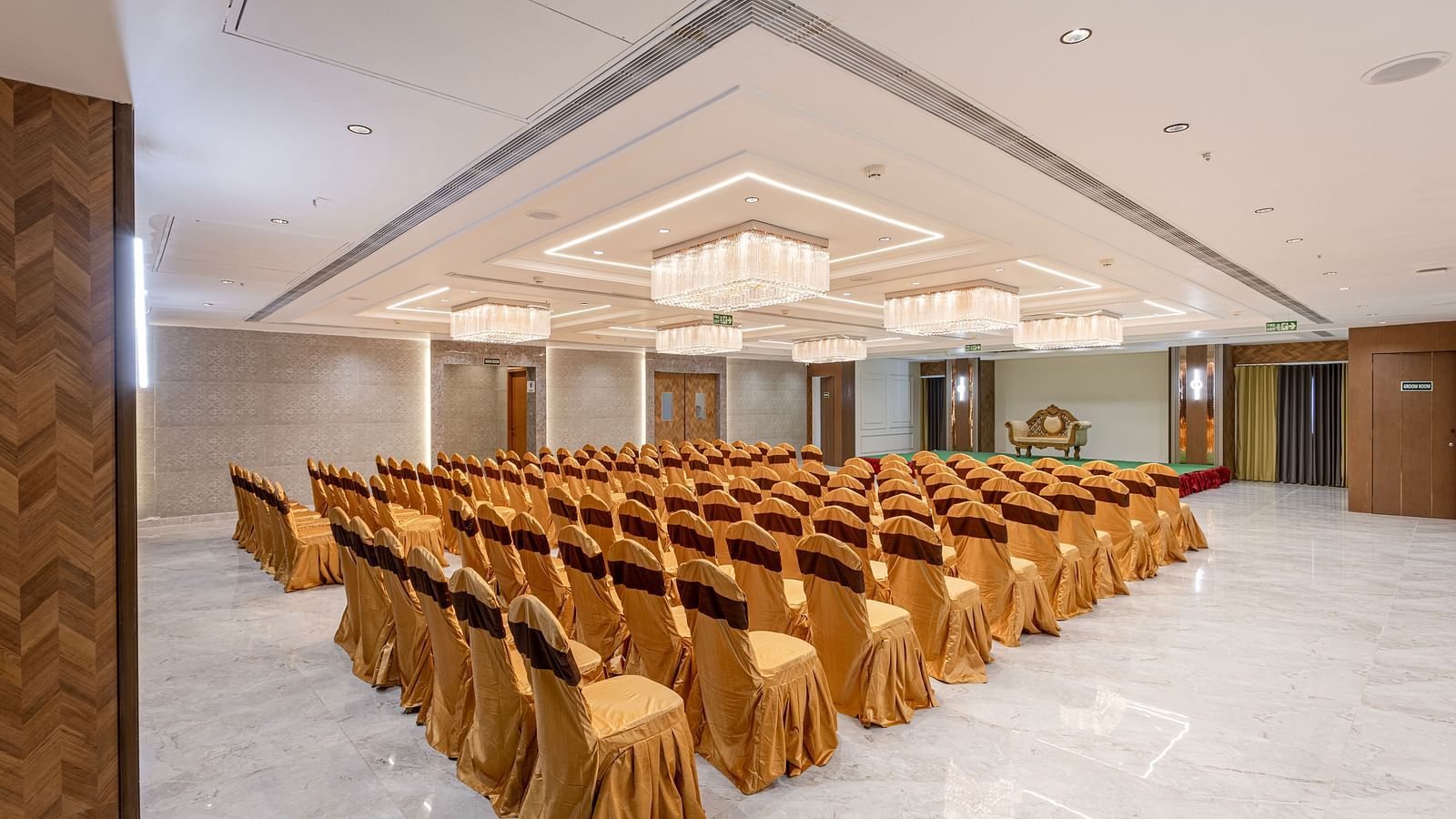 Grand conference hall set up with gold chair covers and chandeliers at Lemonridge Hotels, IDPL Balanagar.