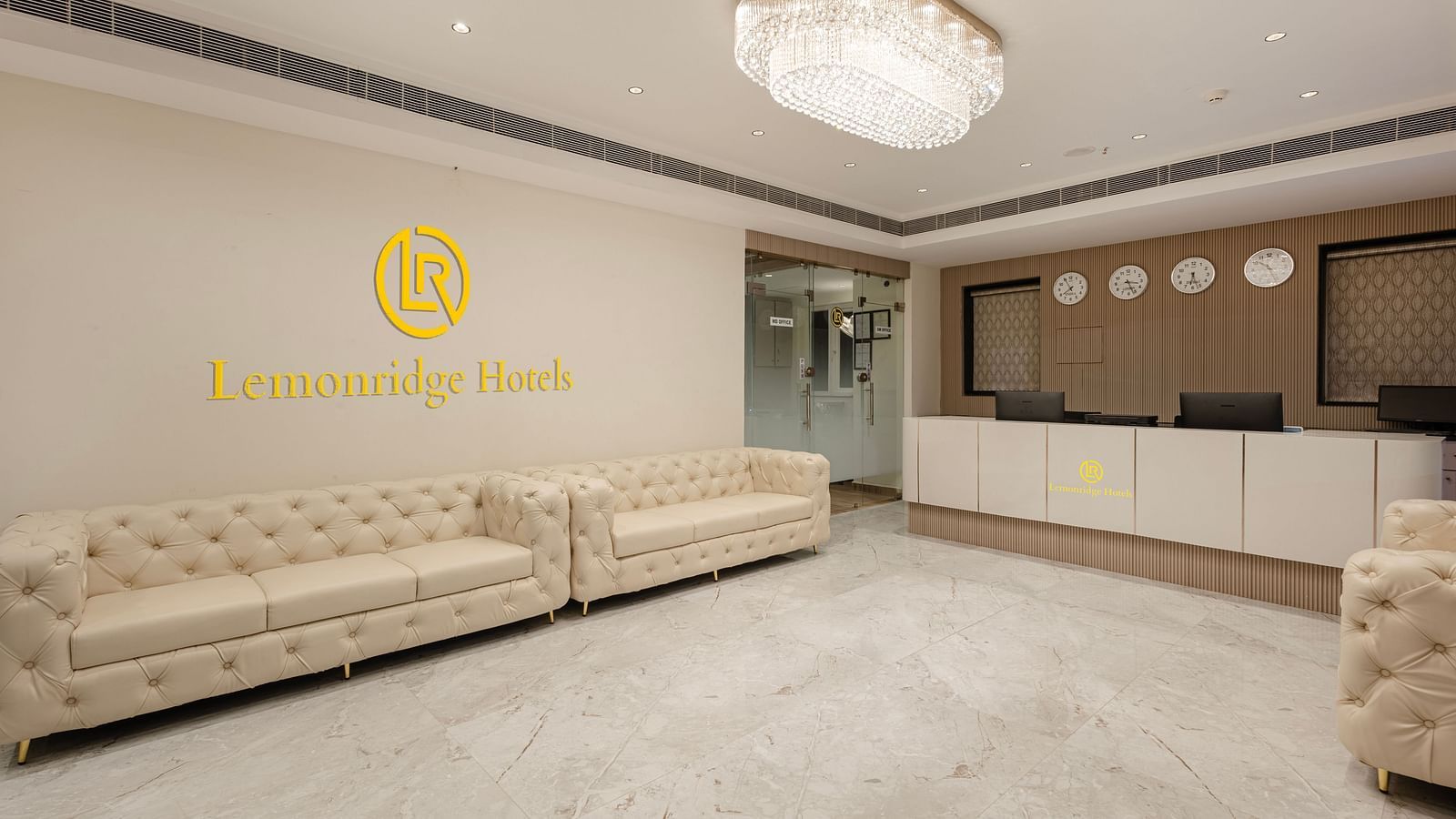 Reception lounge with white sofas and Lemonridge Hotels logo at IDPL Balanagar.
