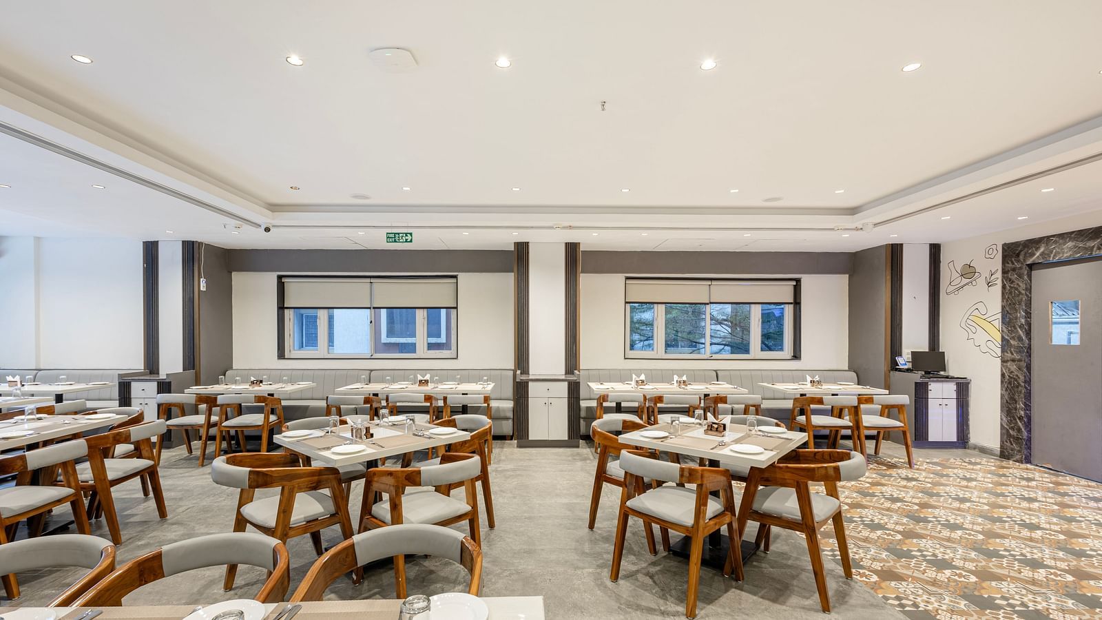 Modern restaurant dining setup with wooden chairs and white tabletops at Lemonridge Hotels, IDPL Balanagar.