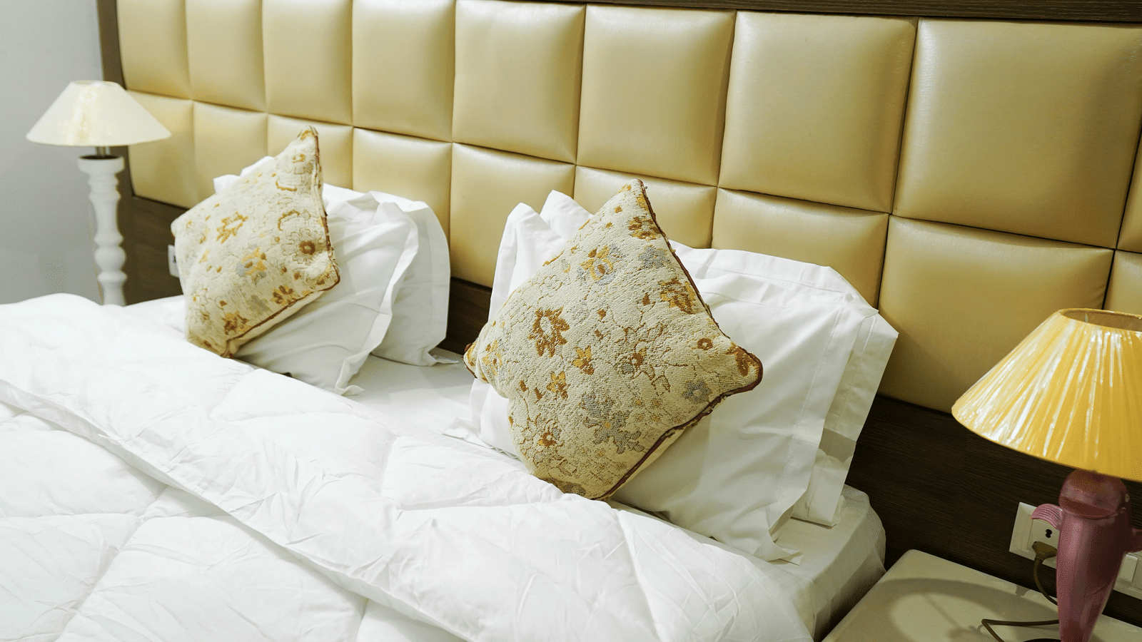 A close-up view of a double bed with patterned cushions - Lime Tree 2BHK Serviced Apartment Near Artemis, Gurgaon