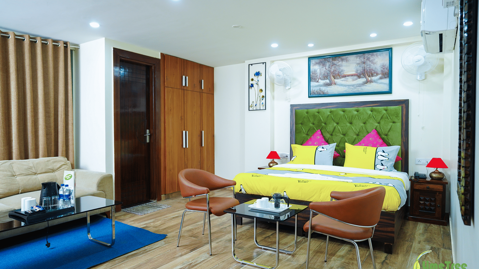 Studio suite at Lime Tree Hotel Near 32nd Avenue with a green-headboard bed, 2 tan leather chairs and a glass tea table.