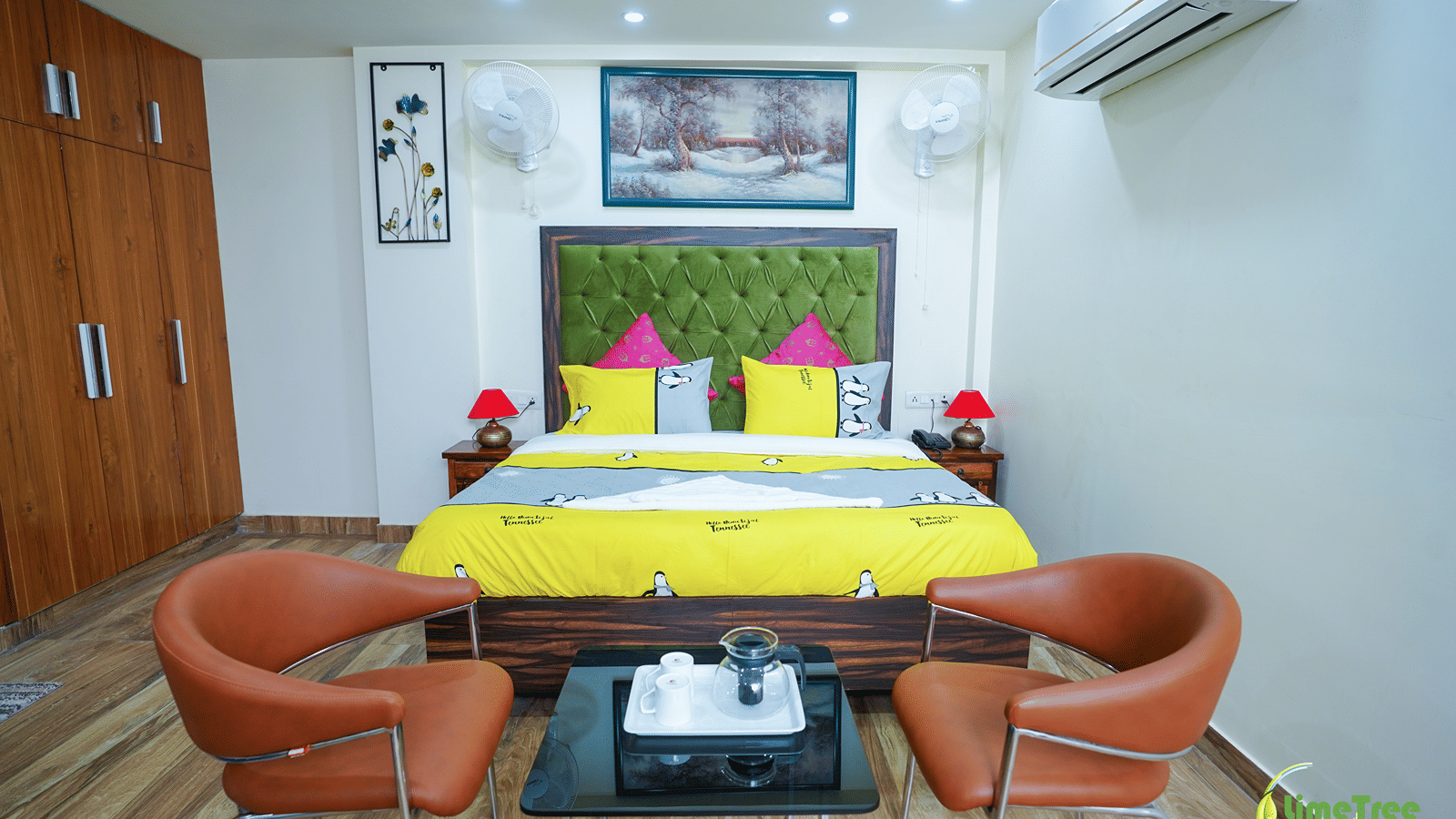 Studio suite at Lime Tree Hotel Near 32nd Avenue with a beige sofa, 2 tan chairs and a green-headboard bed on a blue rug.