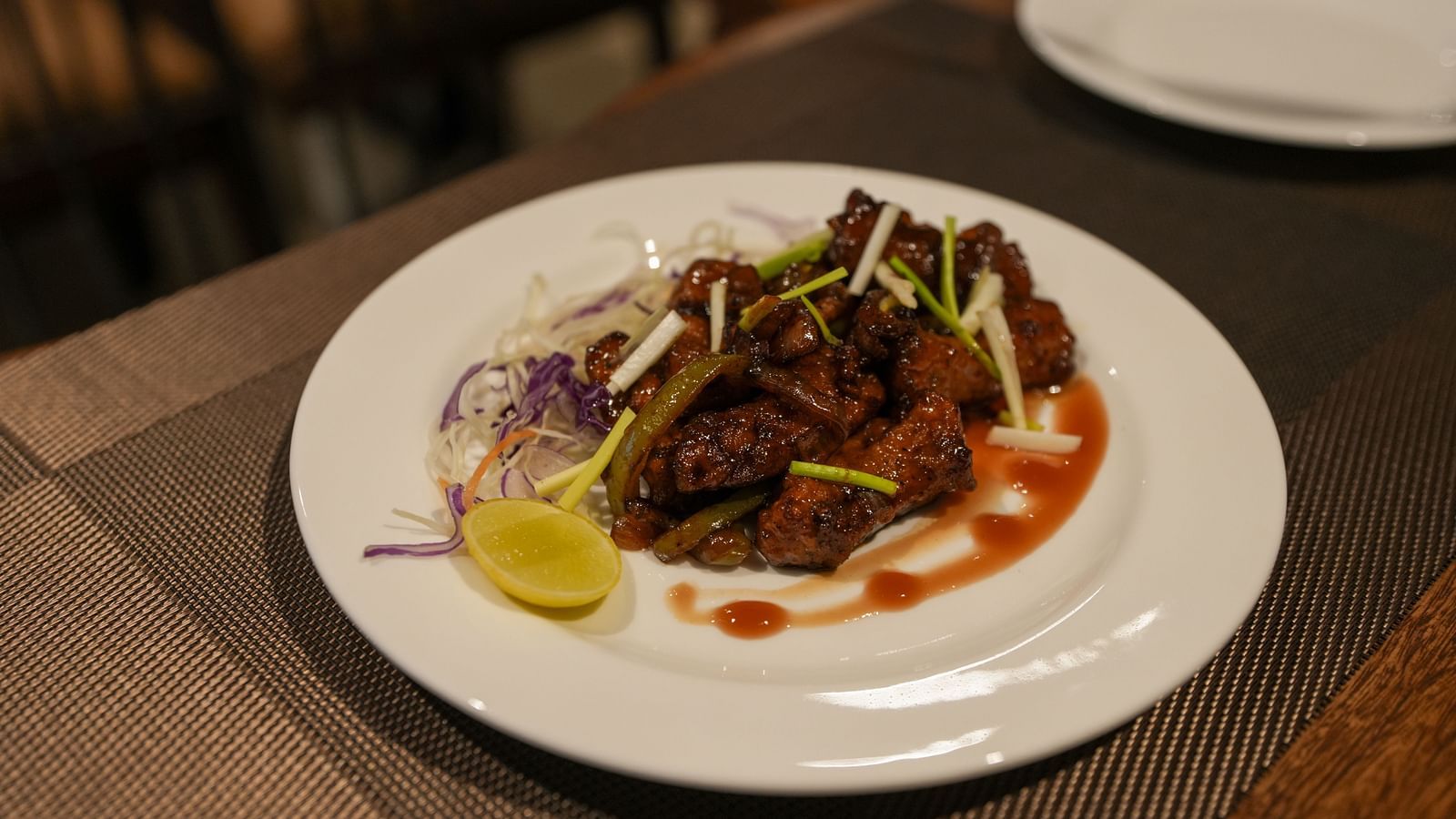 Plate of saucy fried starter garnished with spring onions, cabbage, and a lemon wedge at TGI Livancia Hillside, JC Nagar, Mysore