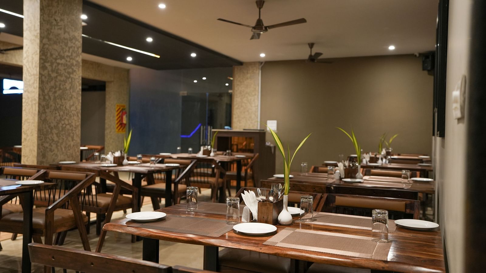Wide view of the restaurant interior showing several tables neatly arranged under ceiling fans at TGI Livancia Hillside, JC Nagar, Mysore