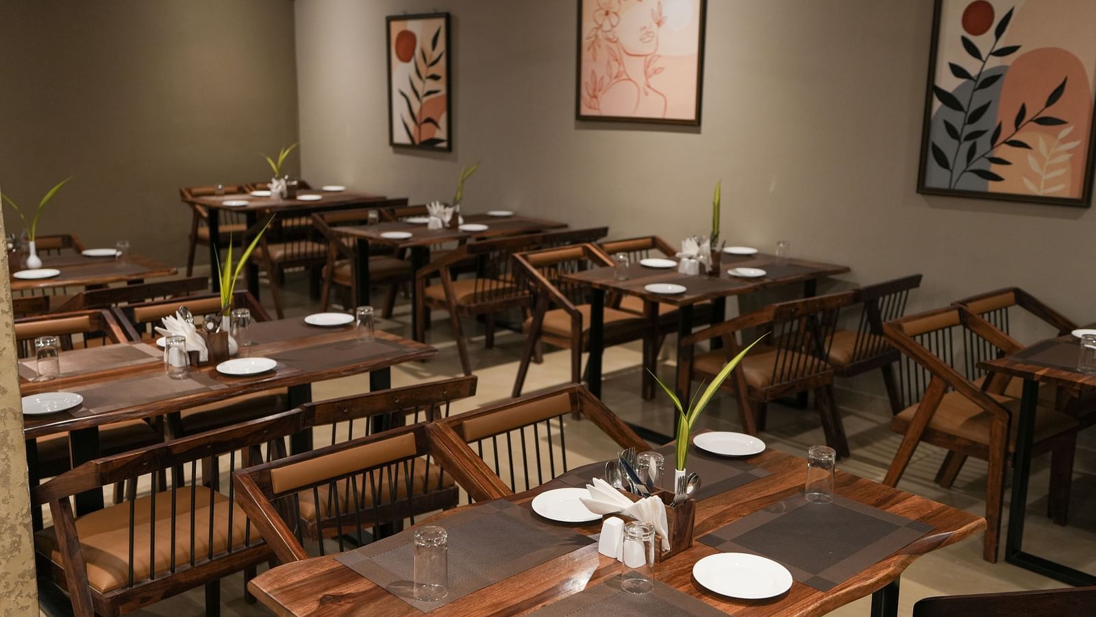 Restaurant seating area with wall art and a focus on clean, minimalist table settings at TGI Livancia Hillside, JC Nagar, Mysore