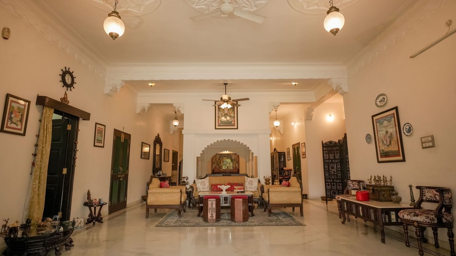 A wide-angle interior view of Mahendra Niwas, capturing a grand hall with luxurious seating arrangements and traditional decor, emphasizing the spacious and ornate design.