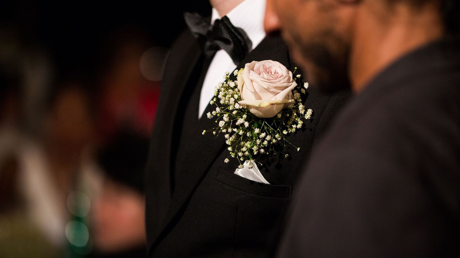 a close up image of a flower corsage tucked inside the pocket of a black tuxedo - Maikhao Dream Villa Resort & Spa, Phuket