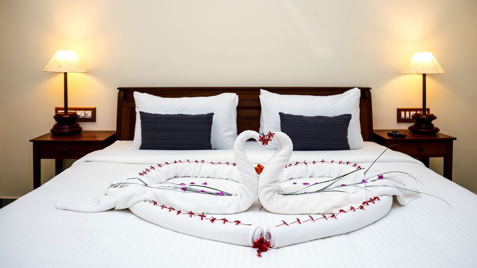 A large bed decorated with towel swans and flower petals | Mango Hill La Serene, Pondicherry